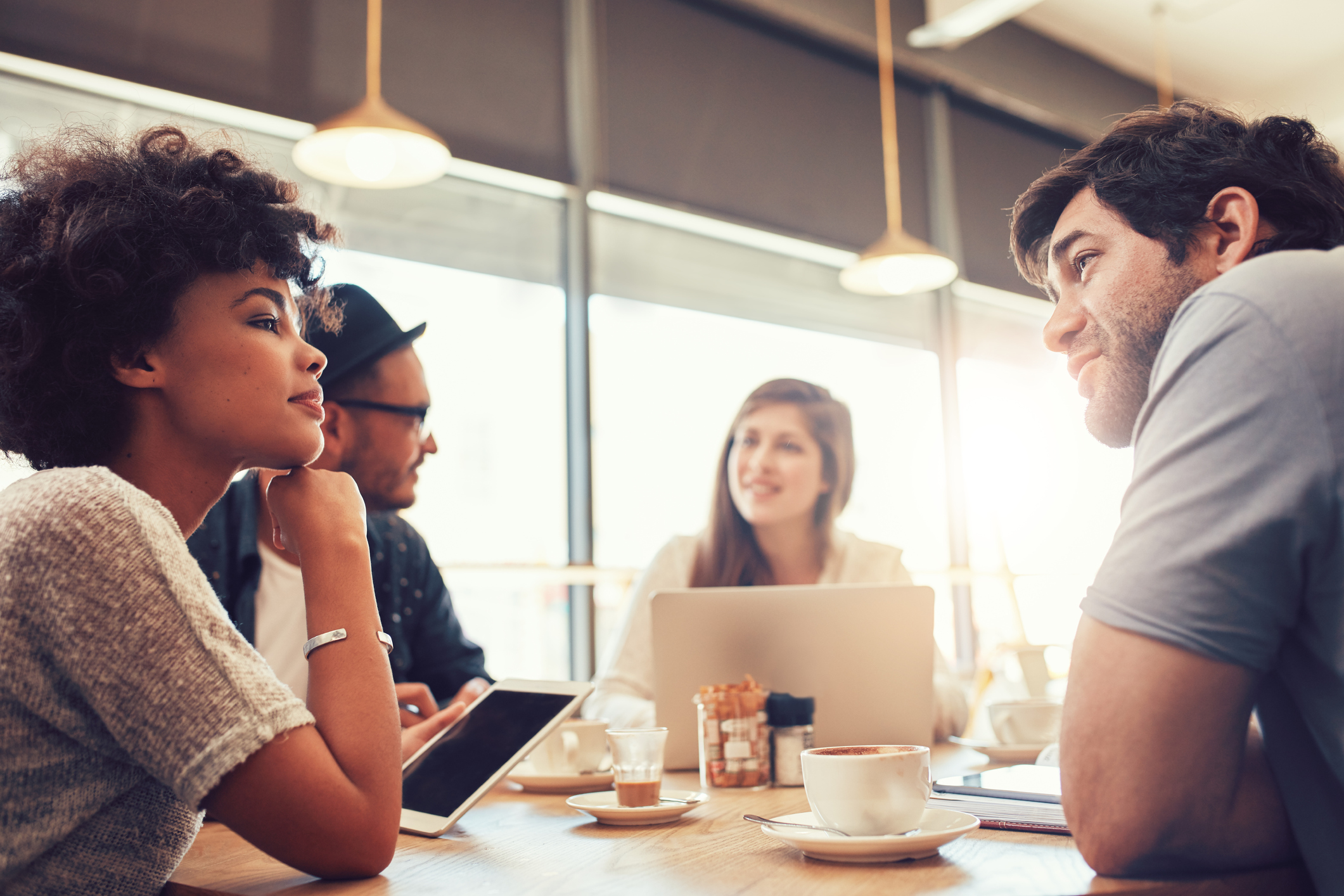 Portrait of group of young people sitting at a cafe and discussing work. Young men and women at coffee shop for startup meeting.