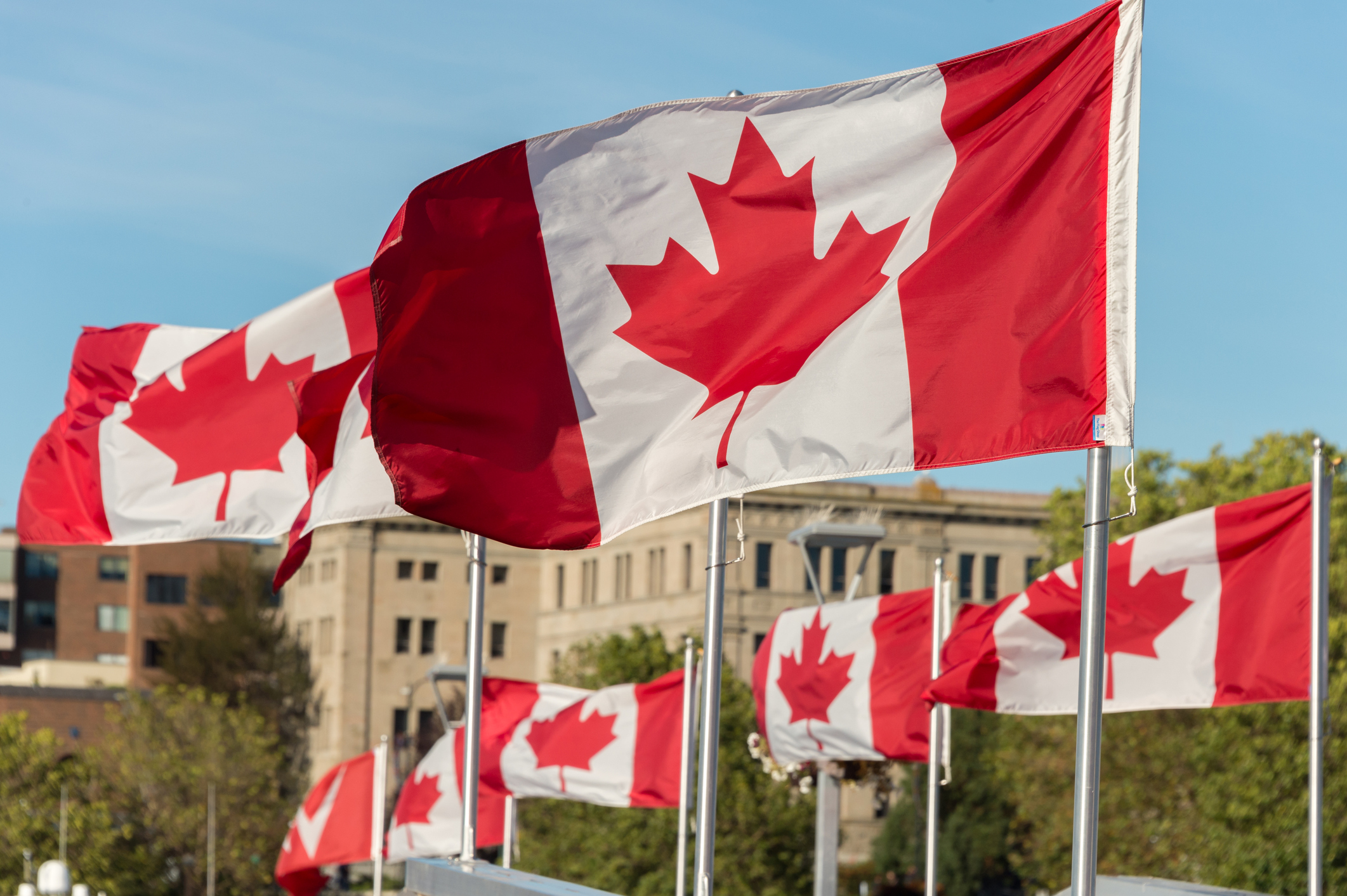 Canada and British Columbia flags waving over blue sky in Vancouver, BC, Canada