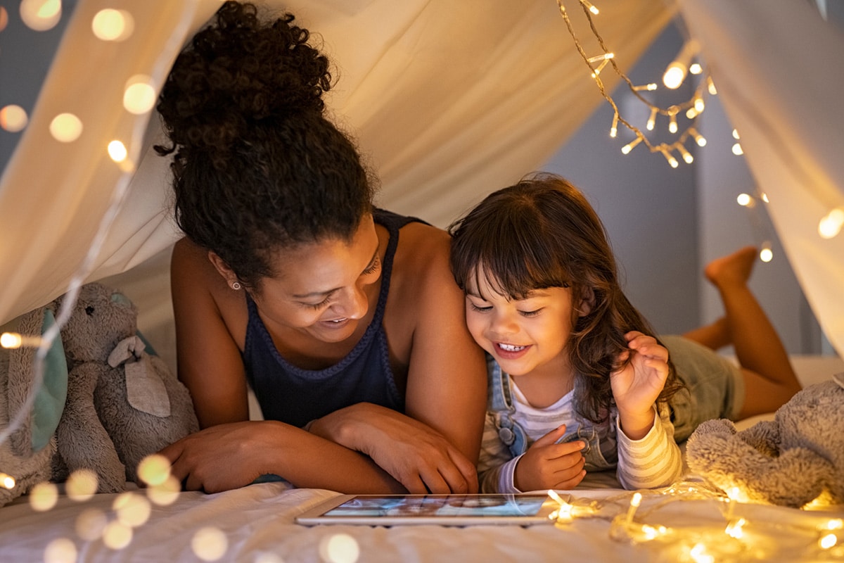 Mom and daughter reading under a blanket fort