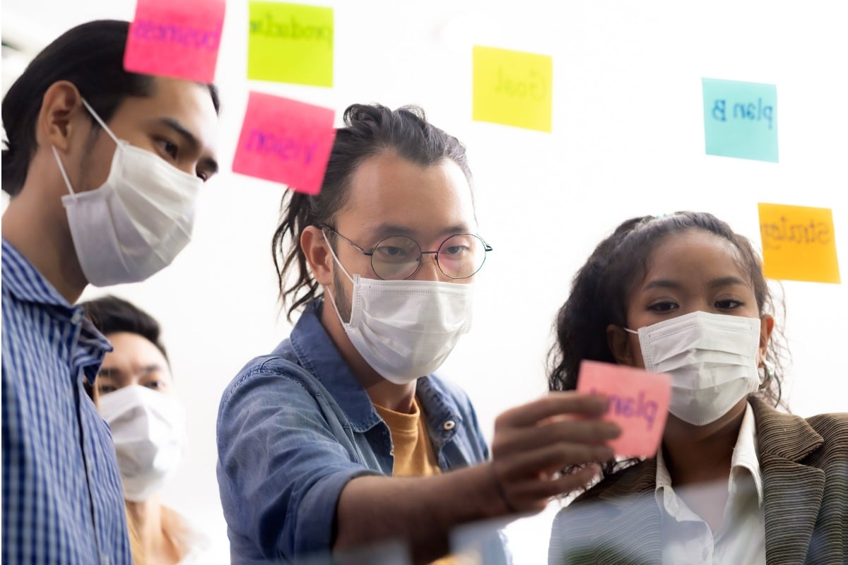Workers wearing surgical masks, placing stickies on a window