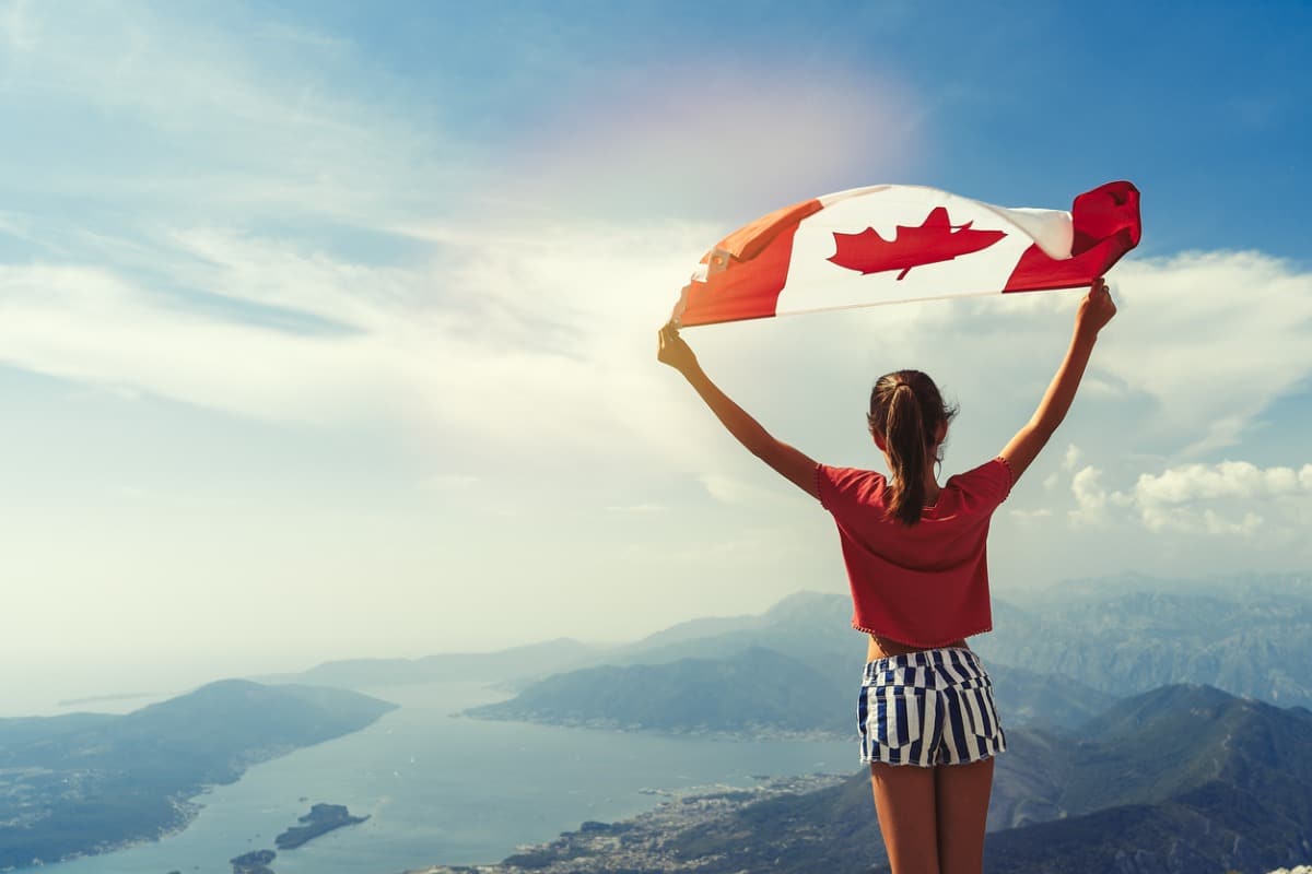 Girl holding Canadian flag on top of mountain