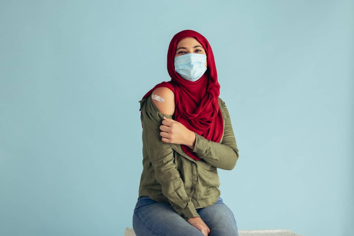 Woman shows the bandage on her shoulder from getting vaccinated.