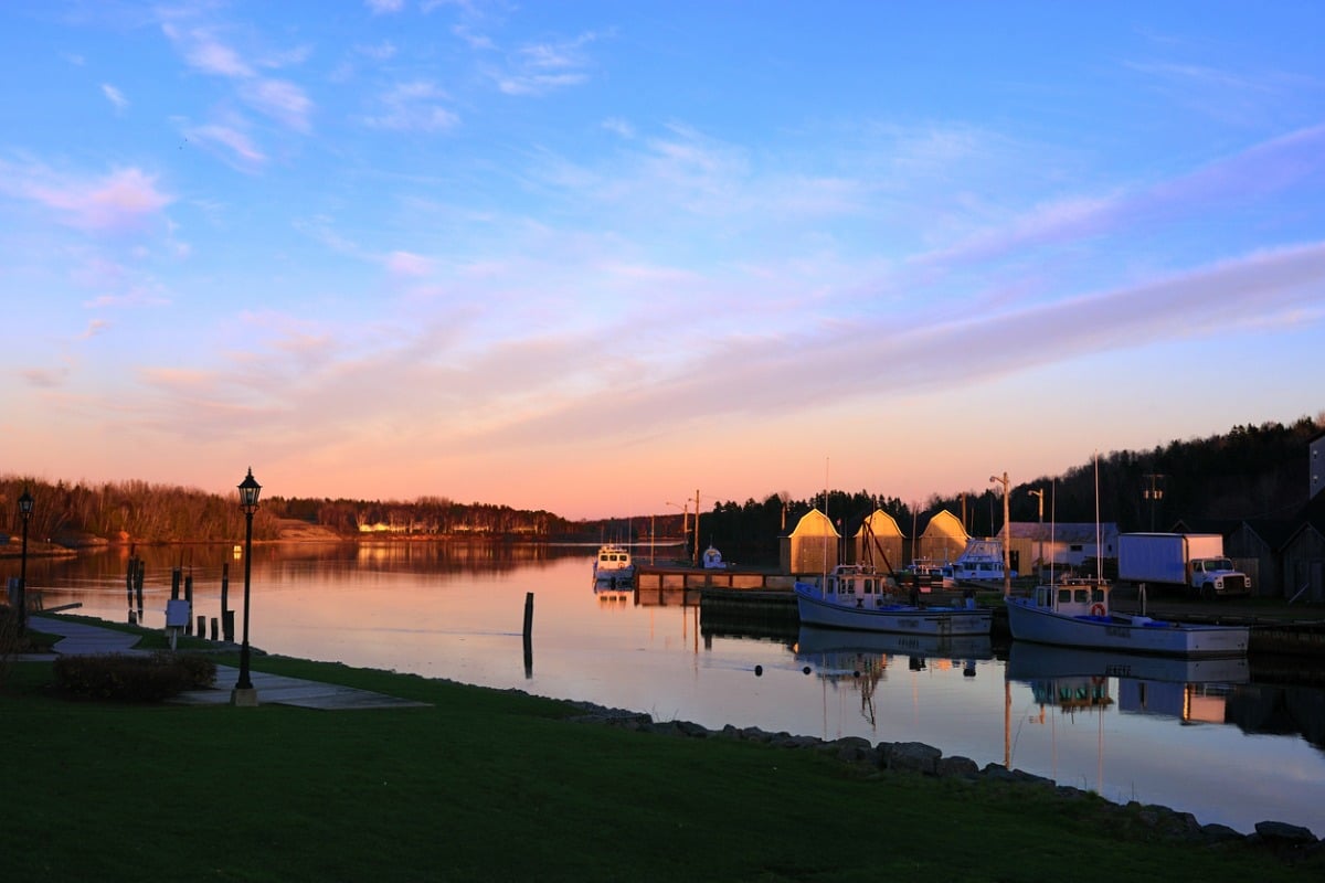 Landscape of Prince Edward Island showing boats in water under the sunset.