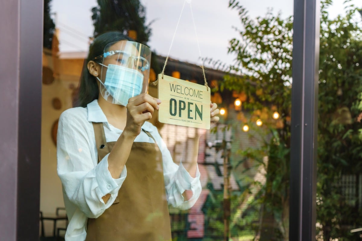 Worker switching door sign to say "Open."
