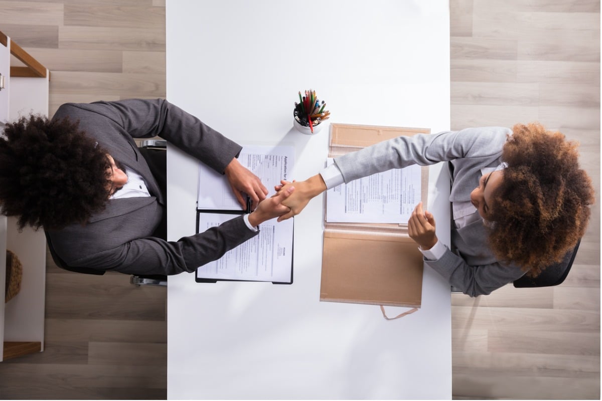 Employer and new hire shaking hands at job interview.