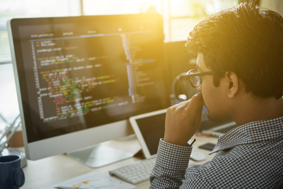 Computer programmer reviewing code on a computer screen