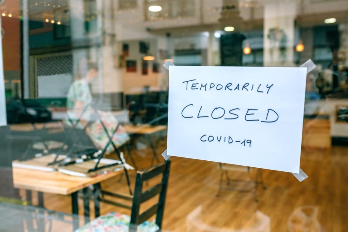 Sign on cafe window that reads, "temporarily CLOSED Covid-19".
