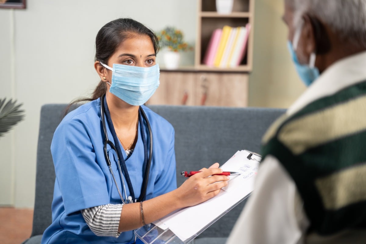Nurse speaking with patient, wearing surgical mask