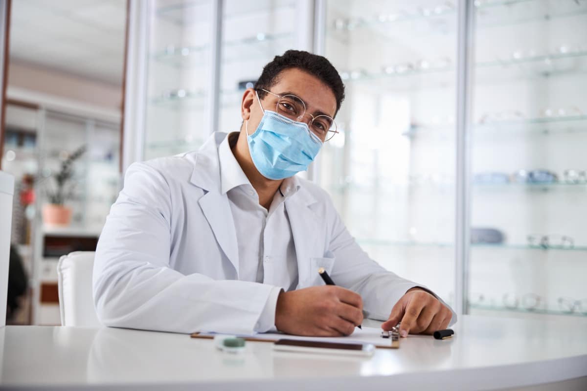 Optometrist facing camera wearing surgical mask.
