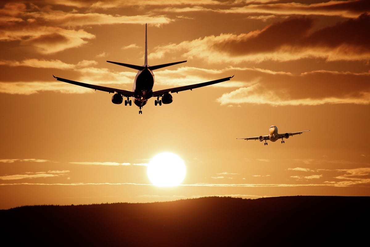 Two airplanes flying during sunset.