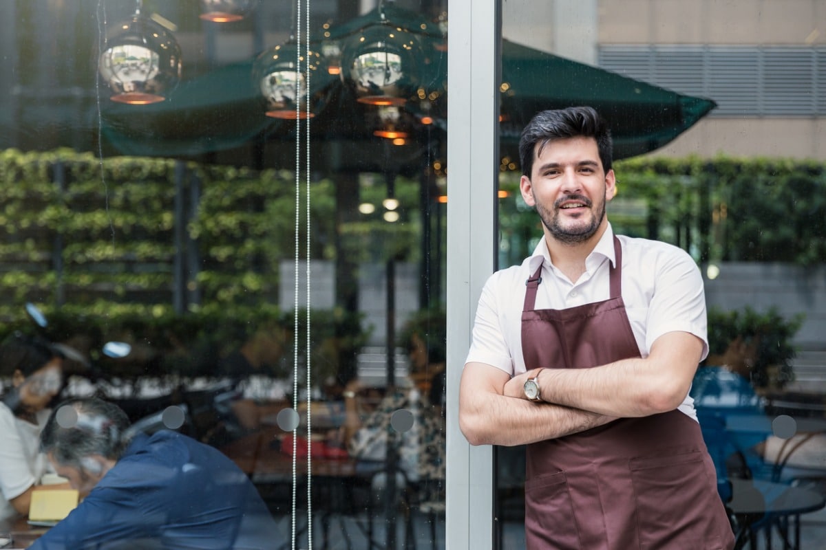 Restaurant manager stands outside restaurant.