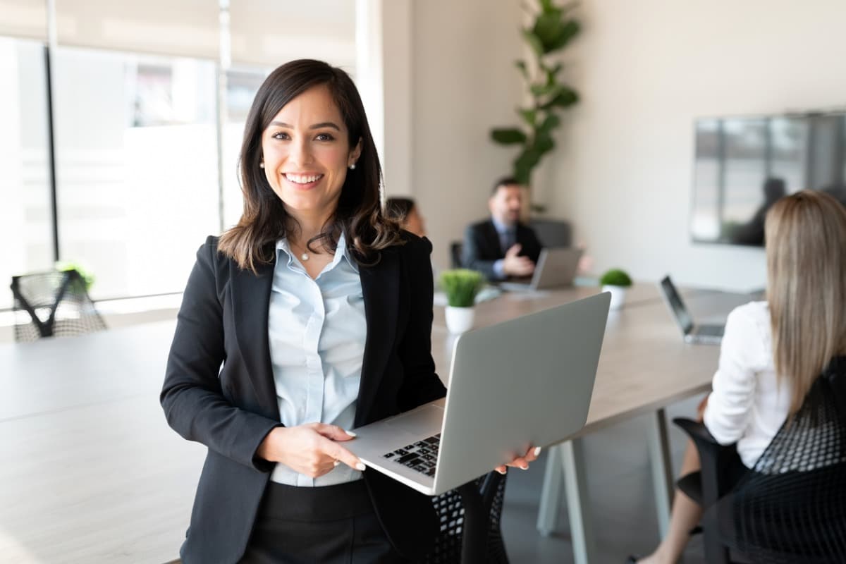Manager holding laptop, smiling facing camera