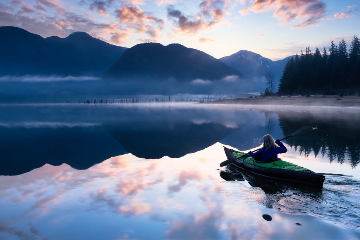Kayaker on reflective lake in the Canadian Rockies.