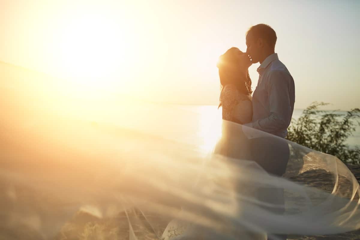 Bride and groom kissing at sunset