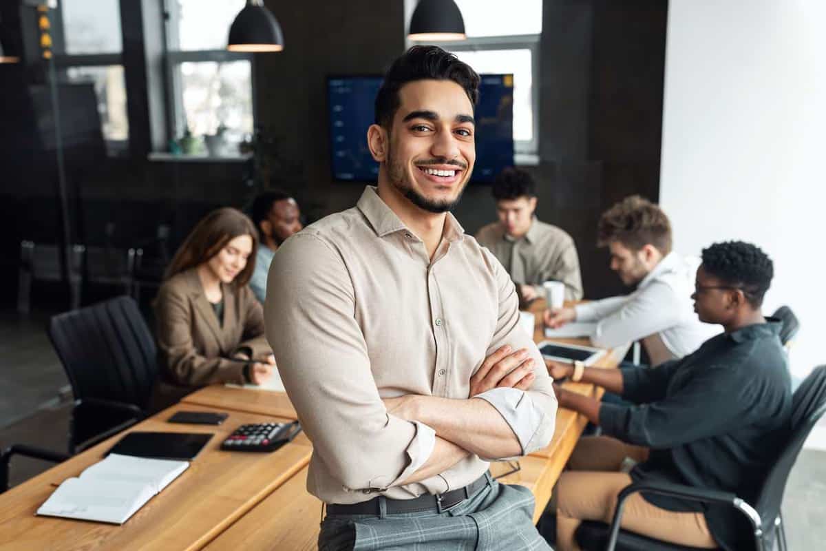 Man standing with arms crossed in front of board room table