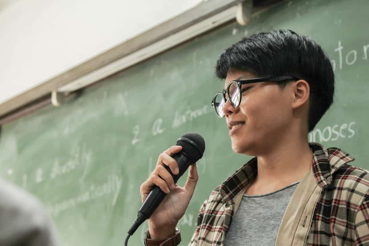 Student in front of a whiteboard with a mike