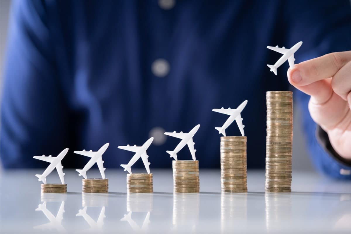 man placing small toy airplanes on stacks of coins