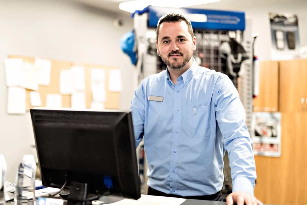 Man standing by a computer smiling