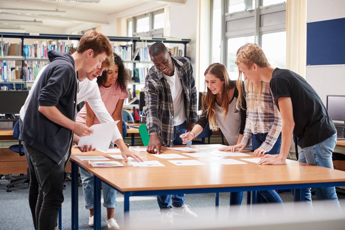group of youth working together standing around a table
