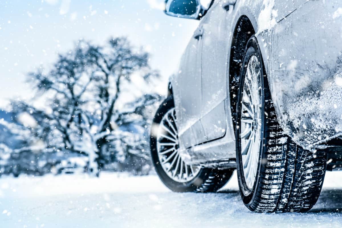 car driving in the winter on a snowy road, tree up ahead in background