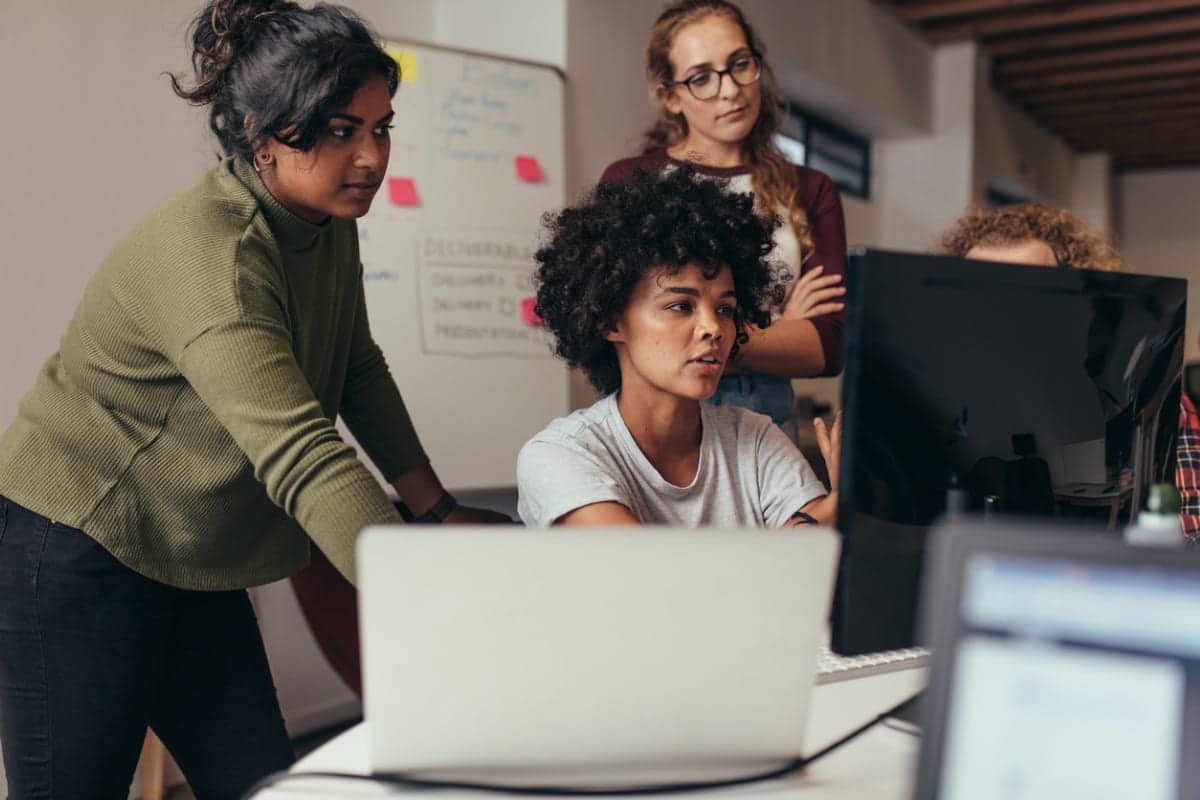 Three women working together on a project at a computer