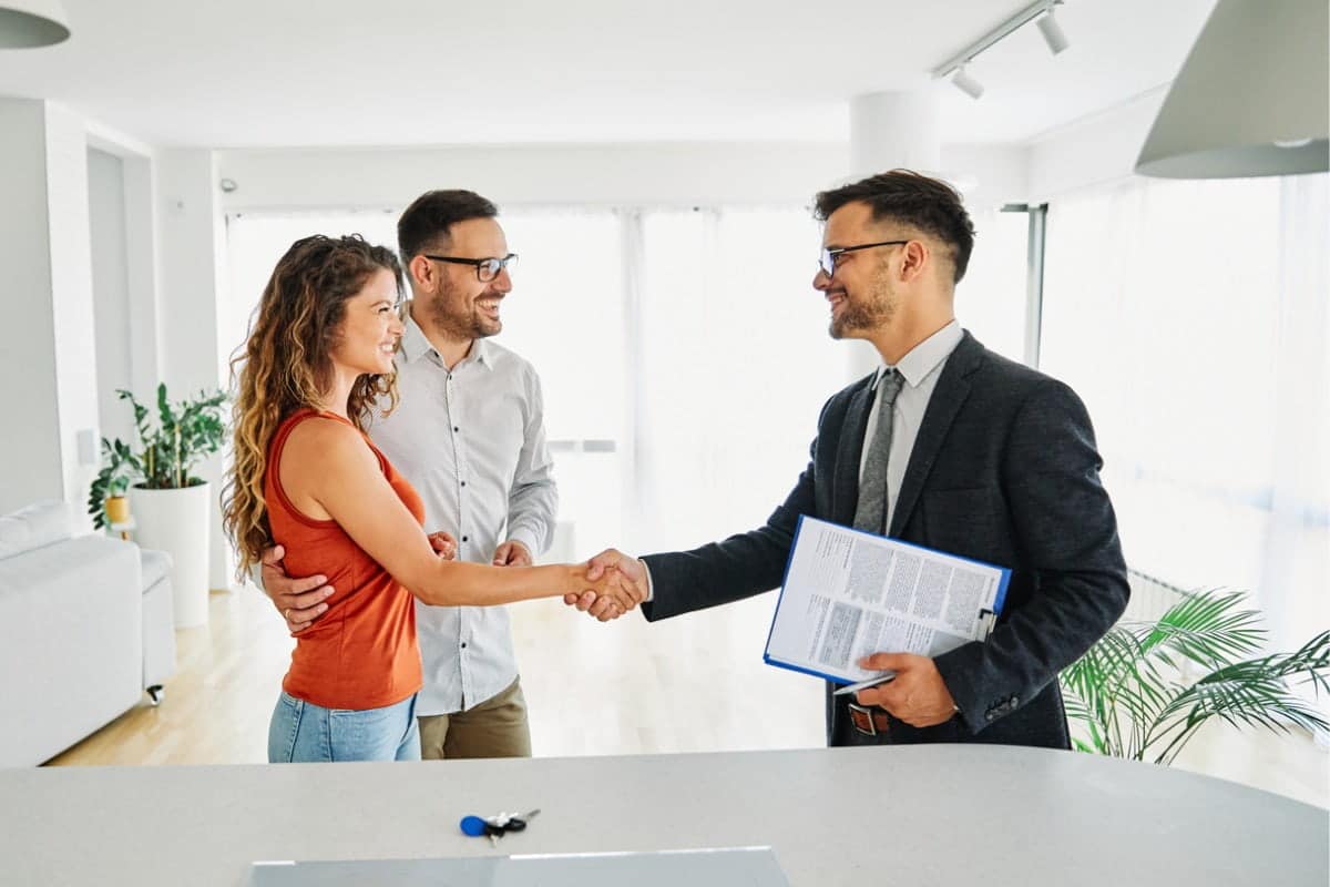 Real estate agent with couple shaking hands closing a deal