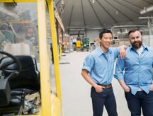 Portrait of workers near forklift in manufacturing plant