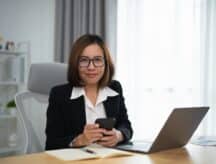 Woman holding and using mobile to work at home