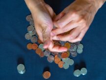 overhead image of two hands being used to count coins
