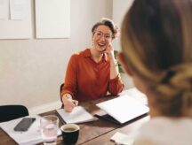 An interviewer looks to an interviewee in an office room.