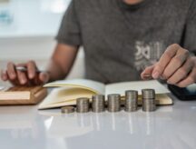 Young man and pile of coins to plan increasing savings strategy with pile of coins for future planning fund.