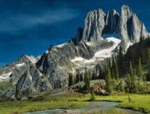A mighty mountain in British Columbia stands tall on a bright, cloudless summer day,.