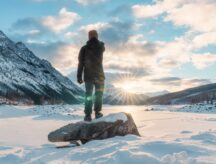 A man looks at the rocky mountains and frozen lake in winter at Medicine Lake, Alberta, Canada