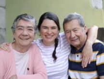 A young woman stands in between elderly couple
