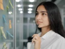 A young woman ponders over post it notes