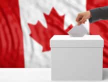 A hand inserts a vote in a voting booth.