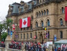 A crowd of people clothed in red walking near Parliament Hill on Canada Day.