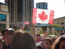 A group of individuals waving Canadian flags at Mississauga City Centre on Canada Day.