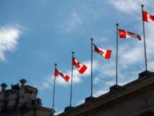 Canadian flags on top of building with blue sky