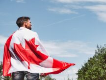 A man holds a Canadian flag across his back