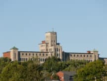 Semi-distant view of Université de Moncton on a sunny day with some trees in the foreground.