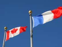 A Canadian and French flag blowing in the wind.