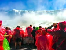 A group of people on a boat, observing Niagra falls up close.