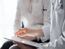 Doctor's appointment, as a doctor shows a patient a tablet with medical information on it.