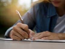 A young person writing with pen and paper