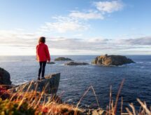 Woman in red jacket looking into the distance on North Twillingate Island in Newfoundland and Labrador.