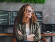 Smiling woman in glasses surrounded by screens