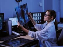 Female radiologist sitting at a work station and examining an X-ray scan.